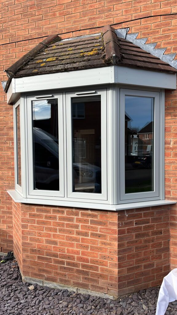 UPVC Casement Windows 30 White uPVC bay window with three glazed sections beneath a small tiled roof